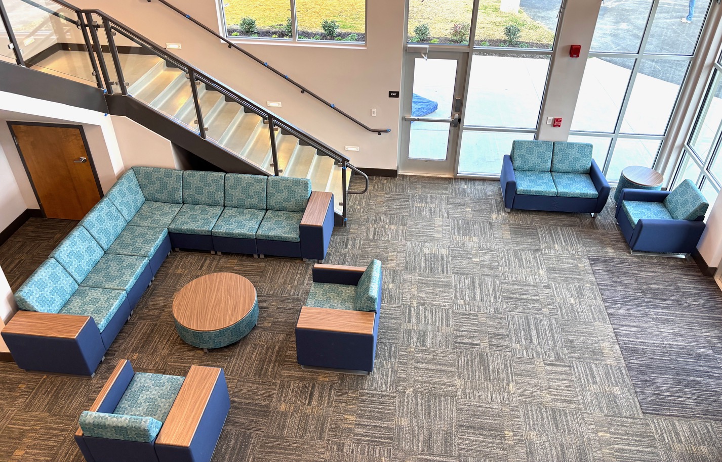 Modular dark gray carpet tiles from Yoder Floors with a shades of grey variegated pattern on the floor of a high-traffic campus student seating area, offering a clean, professional, and easily maintained surface.