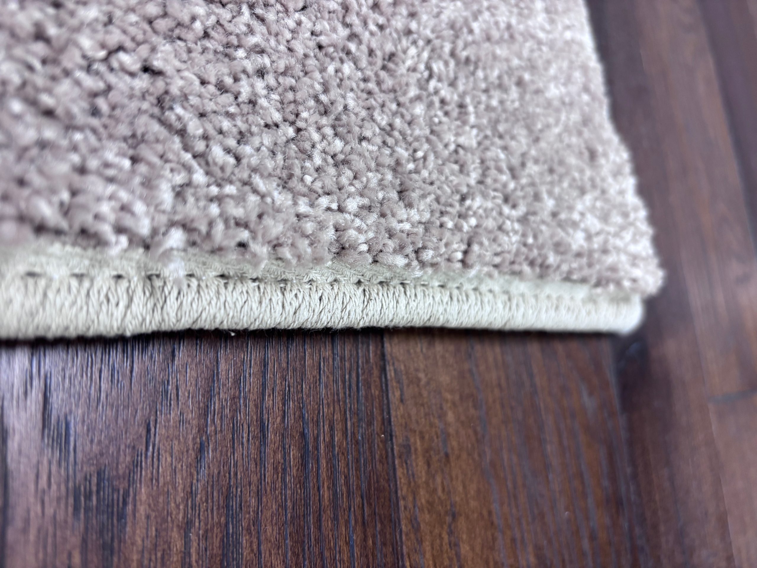 A beige striped carpet stair runner from Yoder showing a close-up of the serging tape finished edge.